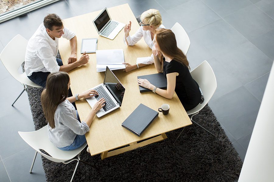 Contact - Group of Employees Sitting Around Table in the Office Working Together