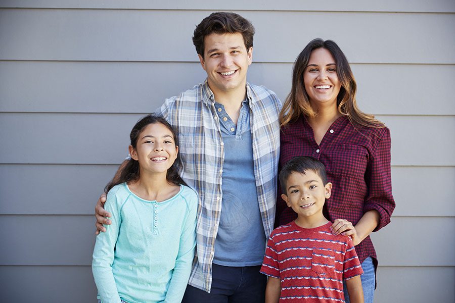 Personal Insurance - Portrait of Happy Family Standing in Front of Their House
